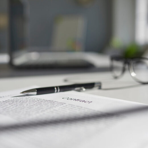 Some paper documents ready for signing on table. Employment or insurance contract agreement, pen, and glasses placed on office desk. Close up. Soft, selective focus